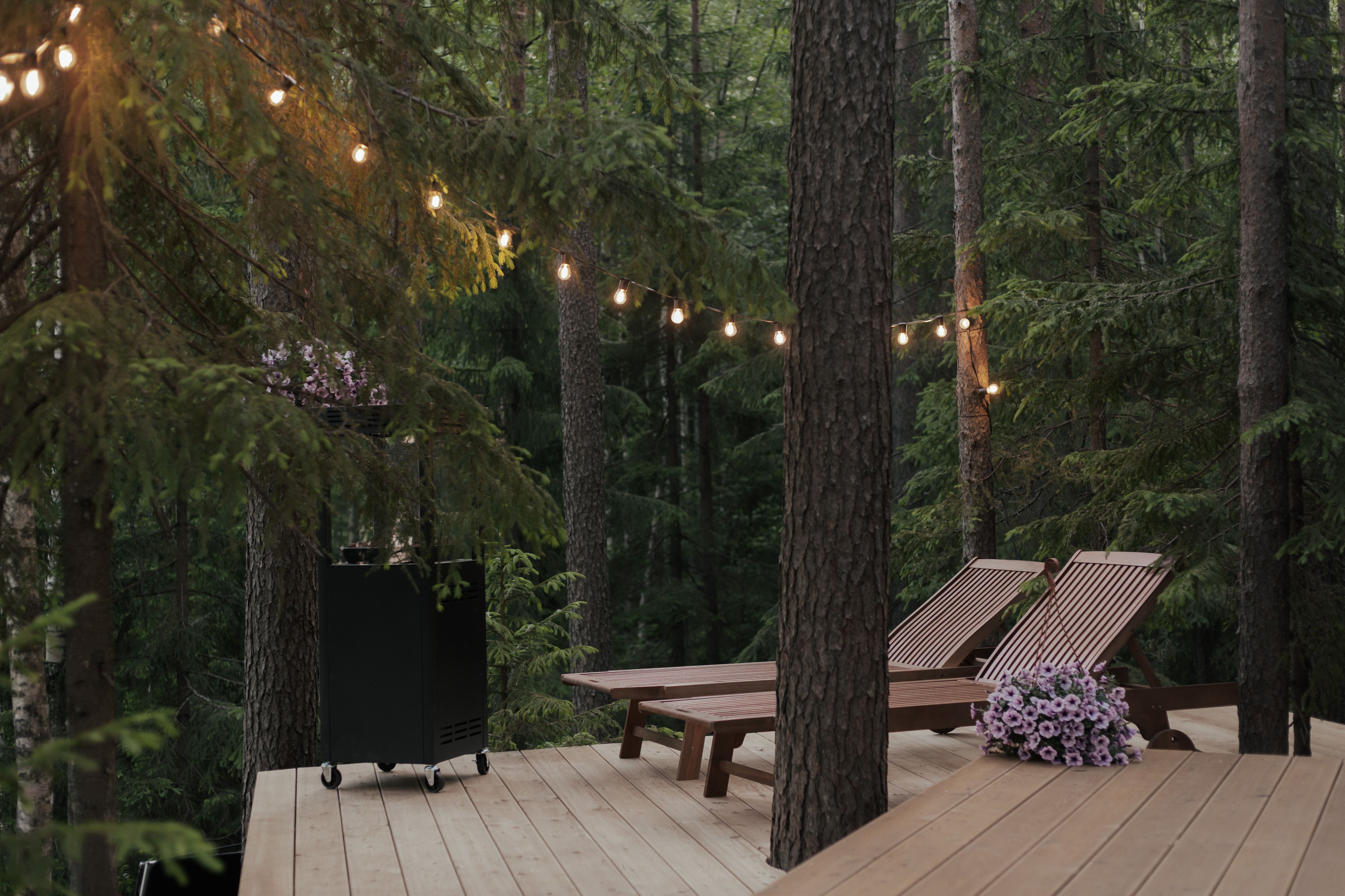 Wooden forest deck with sun loungers and string lights for relaxed cabin entertaining.